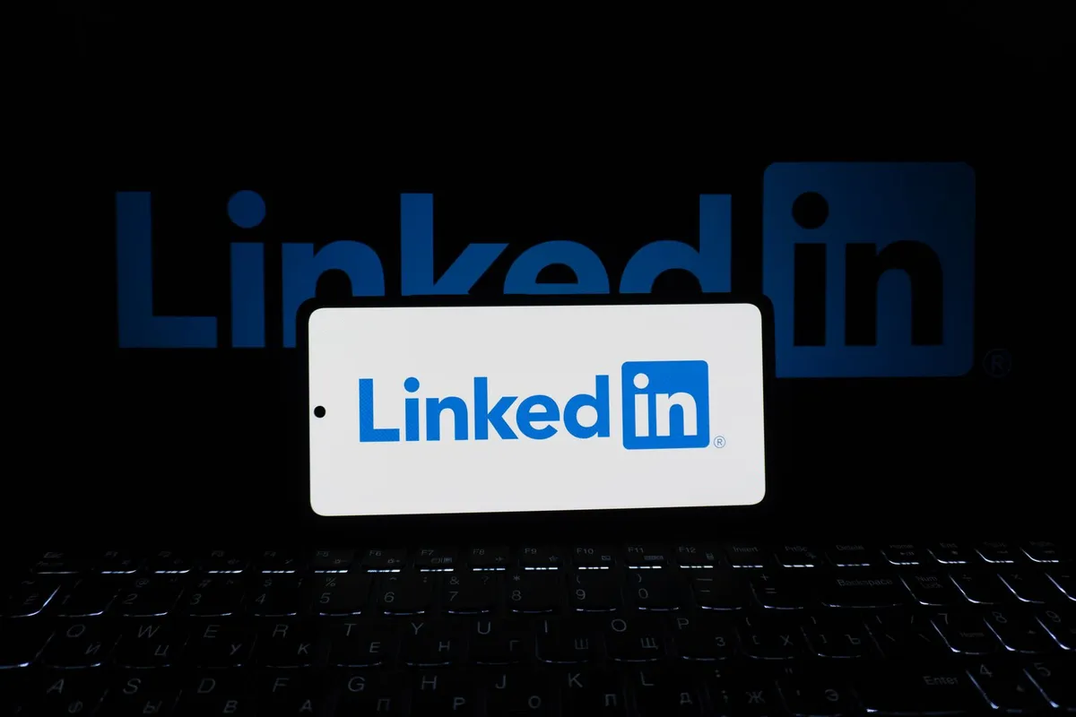 LinkedIn-appen vist på en mobil og en laptop på et skrivebord.