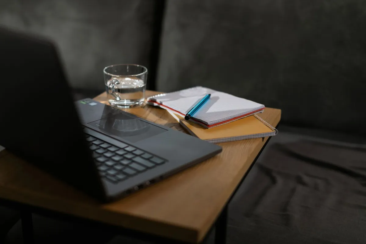 En ryddig arbeidsplass med laptop og notatbøker for skriving.