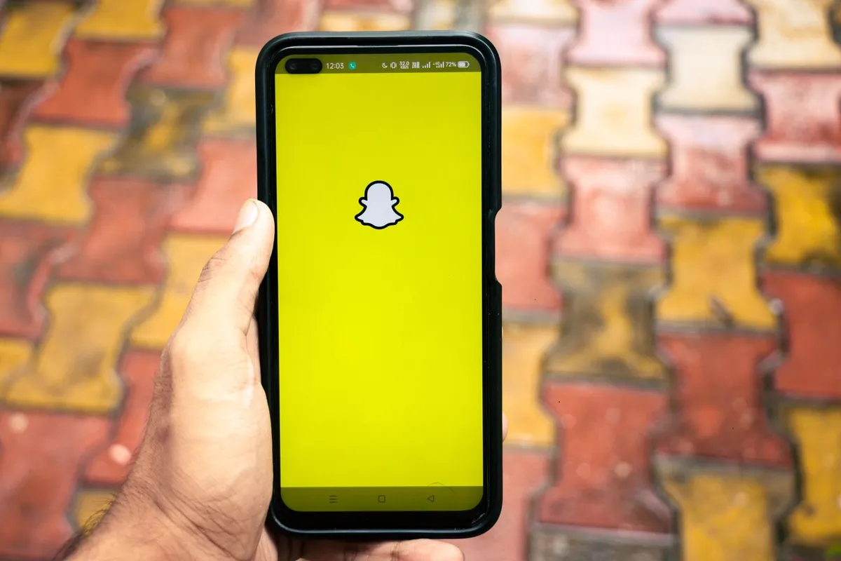 En person holder en mobil med Snapchat-appen åpen utendørs.